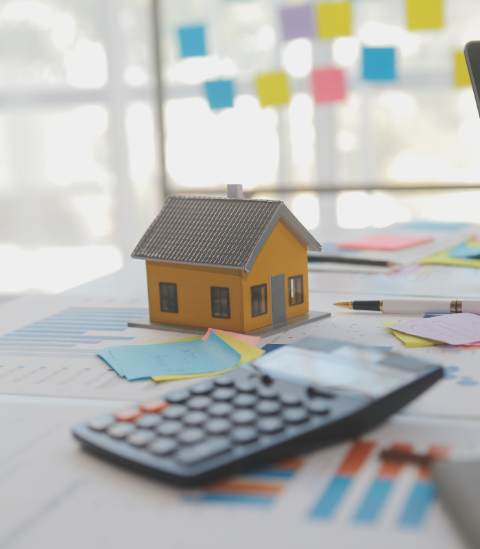 Maquette de maison sur plans avec calculatrice, illustration d’une estimation immobilière par L’Avenue à Albi