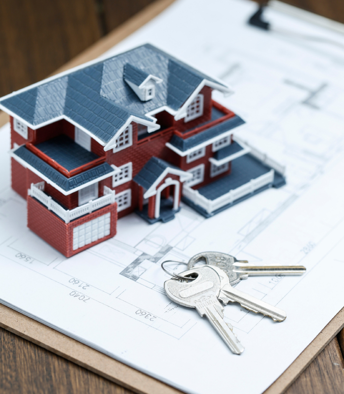 Agent immobilier remettant des clés au-dessus d’une maquette de maison, accompagnement achat et vente par L’Avenue